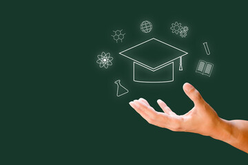 Hand with white line graduation cap on green background. Education and learning concept.