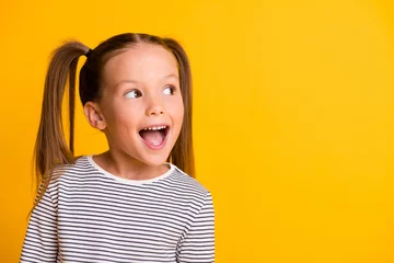 Foto op Canvas Portrait of happy excited amazed open mouth kid child girl look in copyspace isolated on yellow color background © deagreez