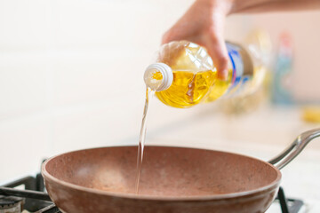 woman hand pour cooking oil on the pan at home