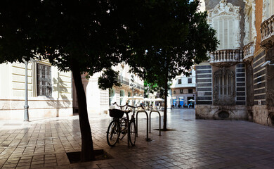 Summer sunny day on the street of Valencia. Shade from trees on bicycles. People are resting in a cafe. Spain