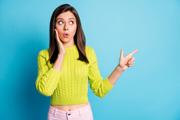Photo of young amazed shocked girl point finger empty space hand touch cheeks isolated over blue...