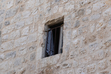 Fototapeta na wymiar An arabic headscarf with a national pattern hangs on a metal lattice in a building window on the Via Dolorosa Street in the old city of Jerusalem in Israel