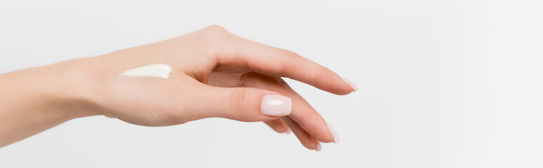 partial view of woman with cosmetic cream on hand isolated on white, banner