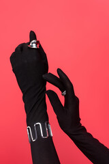 cropped view of female hands in black gloves with rings and bracelet isolated on red