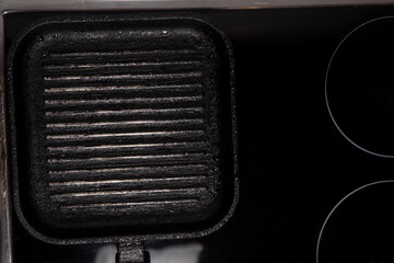 fempty square grill pan on black induction hob. lat lay top-down composition