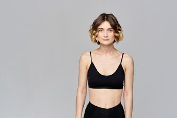 Obraz premium A slender woman is gesturing with her hands on a gray background Sport Fitness figure