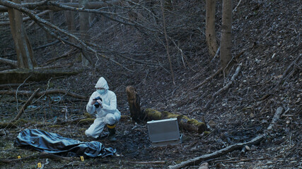 Detectives are collecting evidence in a crime scene. Forensic specialists are making expertise. Police investigation in a forest.