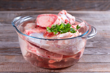 Saucepan with soup or bone broth meat and vegetables cooking ingredients and spices on the table