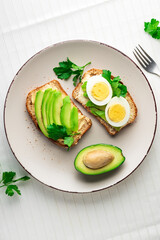 Toast with avocado and egg on white plate. Top view. Healthy breakfast