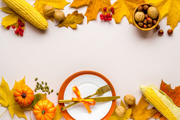 Thanksgiving concept with place setting pumpkins and leaves on a dinner table