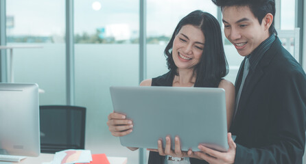 Young male and female using laptop and looking at camera.