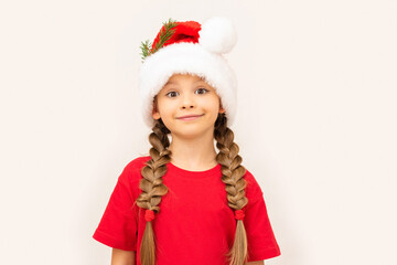 Beautiful little girl posing in a red t-shirt and Christmas hat.