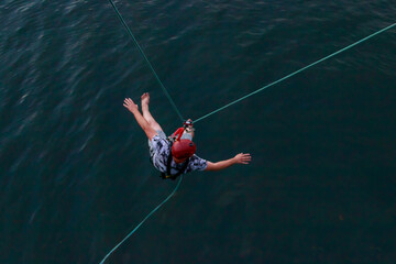 Rope jumping from high altitude of bridge. Bungee jumping from pedestrian bridge over beautiful river