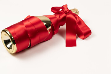 gift bottle of champagne in gold foil wrapped with red silk ribbon bow on white background