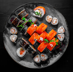 set of sushi roll with salmon, avocado, cream cheese, cucumber, rice, tuna in plate on black background