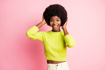 Photo portrait of woman touching afro wig with two hands isolated on pastel pink colored background