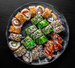 set of sushi roll with salmon, avocado, cream cheese, cucumber, rice, tuna in plate on black background