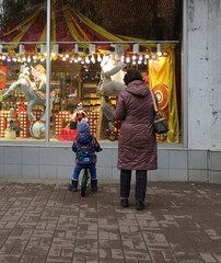 Woman with child look at a colorful shop window on the street
