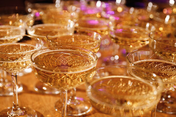 Glasses with Sparkling Wine. champagne glasses over Holiday Bokeh Blinking background. Celebration, party concept.
