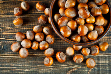 Hazelnuts in a bowl on a brown wooden background. Lots of nuts on an old shabby board.