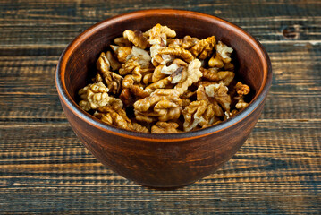 Peeled walnuts in a bowl. Nuts close up on an old wooden board. Food on a shabby table.