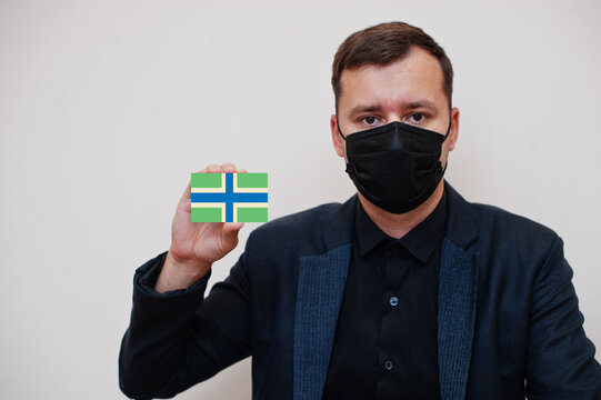 Man wear black formal and protect face mask, hold Gloucestershire flag card isolated on white background. United Kingdom counties of England coronavirus Covid concept.