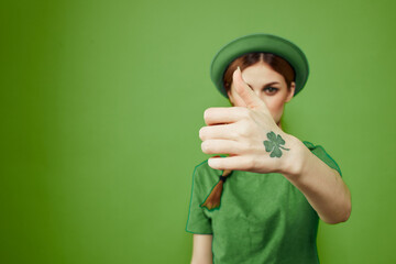 Happy woman with shamrock on St. Patrick's Day in green clothes and a hat on her head gesturing with her hands