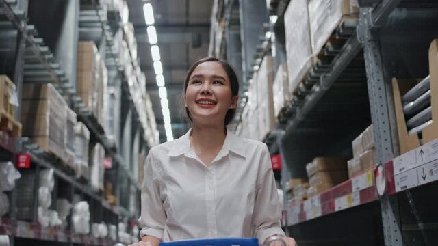 Teenage Asian young woman wearing a white shirt is shopping choosing home decoration. Shop for furniture in the department store. Or construction equipment in the warehouse.