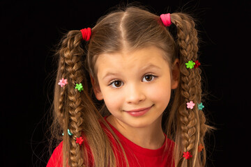 A little girl on a black background smeared with paint.