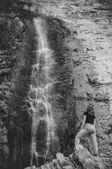 A girl from behind looks at a huge waterfall