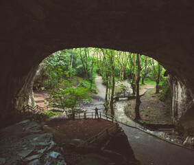 A person in the distance waving under an open cave in nature.