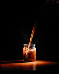 coffee is poured into a transparent jar. product photography of coffee. a wide jet of coffee....