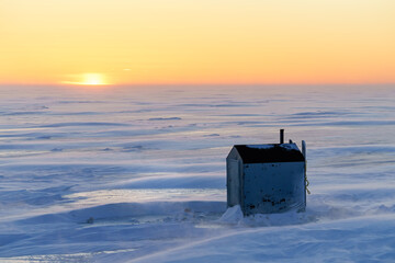 Ice fishing at sunset along the shores of Prince Edward Island, Canada.