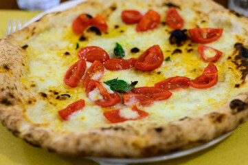Eating of Italian pizza with mozzarella cheese, small red tomatoes and fresh basil