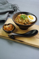 Ramyeon or instant noodles soup from South Korea on black bowl. Served with Kimchi, eggs and leek