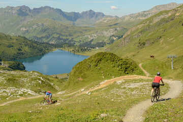 Fototapeta na wymiar People on mountain bike going down the flow track from Jochpass over Engelberg in the Swiss Alps