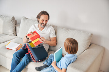 Happy dad and his cute kid sitting on couch