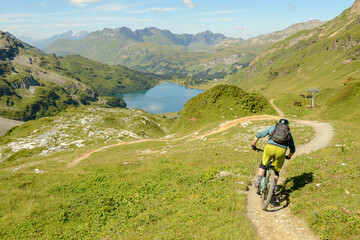 Man on mountain bike going down the flow track from Jochpass over Engelberg in the Swiss Alps