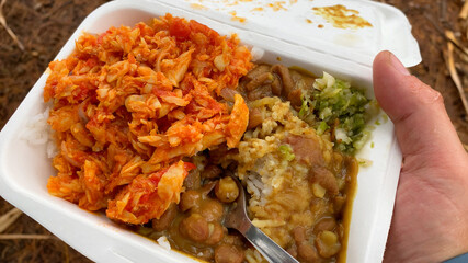 Hand holding a tray of traditional rougail cod curry from Reunion Island