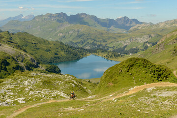 Naklejka na ściany i meble People on mountain bike going down the flow track from Jochpass over Engelberg in the Swiss Alps