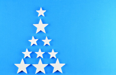 White stars forming a christmas tree on a blue background. Space for text or idea.