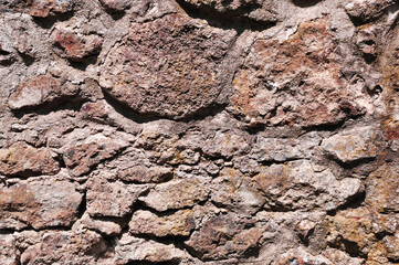 Background, texture, a fragment of a wall made of large and small stones of red color