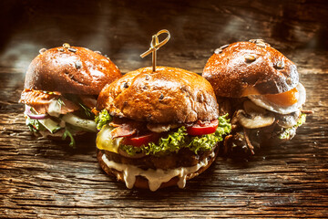 Front view on three large, beef salmon and kebab burgers stuffed with fresh vegetable salad and...