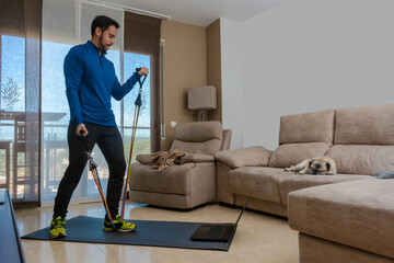 Latin man, doing a workout in his living room with a rubber band