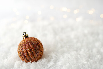 christmas ball laying in the snow on white with lights