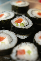 a stack of sushi in a container. sushi with fish close-up. sushi set for clients. ready-to-eat food. a bunch of identical rolls stacked one on top of the other