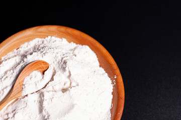 In the lower-left corner of the screen, a Cup of white flour is placed on a dark surface. Wooden spoon.
