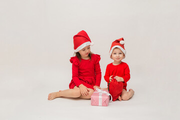 Obraz premium little girl and boy in Christmas hats with gifts on a white background