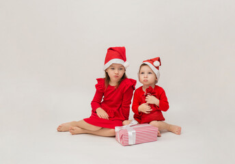 offended little girl and boy in Christmas hats with gifts on a white background