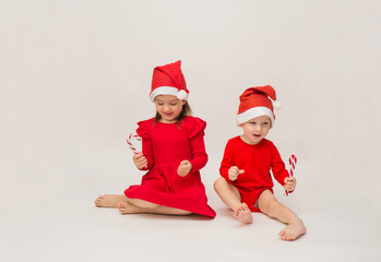 funny little boy and girl in red caps with lollipops on a white background